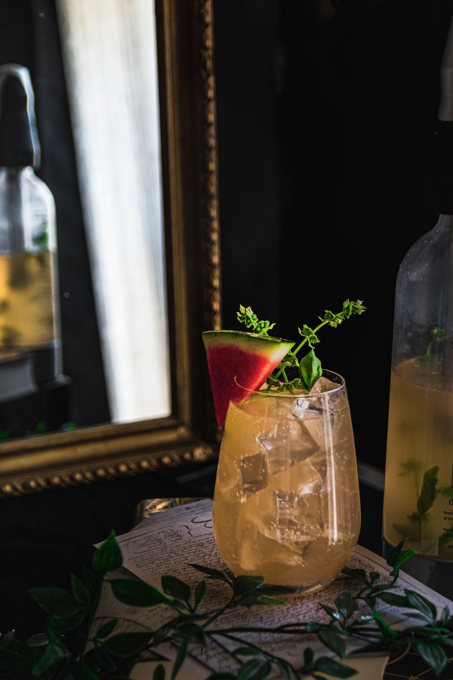 Ein Glas Melonen-Basilikum-Spritz, dekoriert mit einer Melone und Basilikum. 