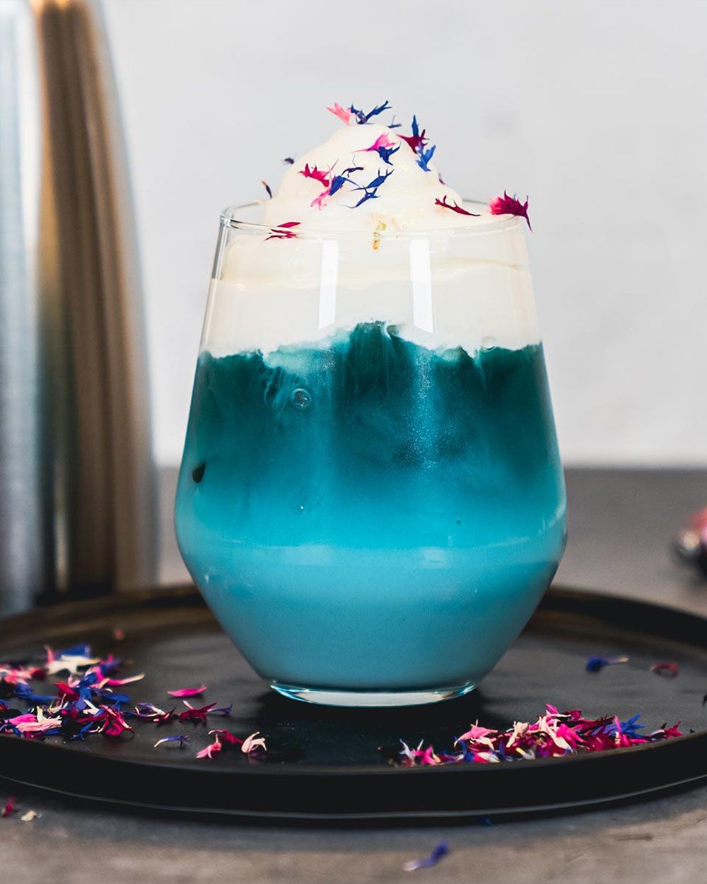 Ein Glas mit einem blauen Getränk mit Cream Cheese Topping. 