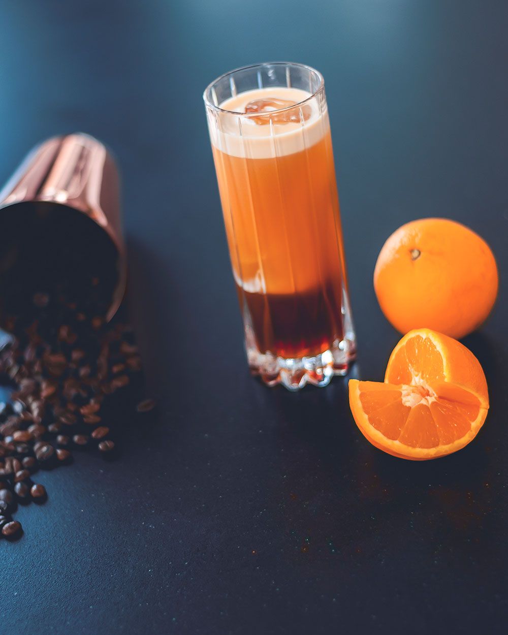 Ein Glas mit Fruity Tonic, daneben Kaffeebohnen und Orangen. 