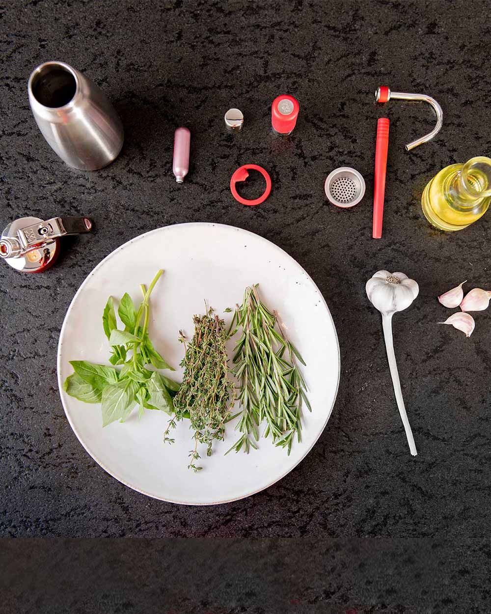 Alle Zutaten und Utensilien für Gartenkäuteröl aufgelegt. 