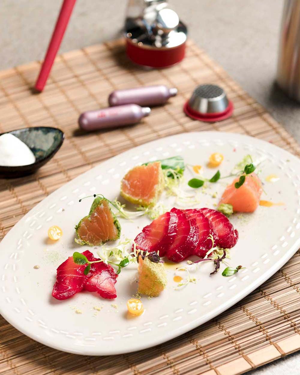 Ein Teller mit mariniertem Lachs, daneben zwei iSi Charge Kapseln.