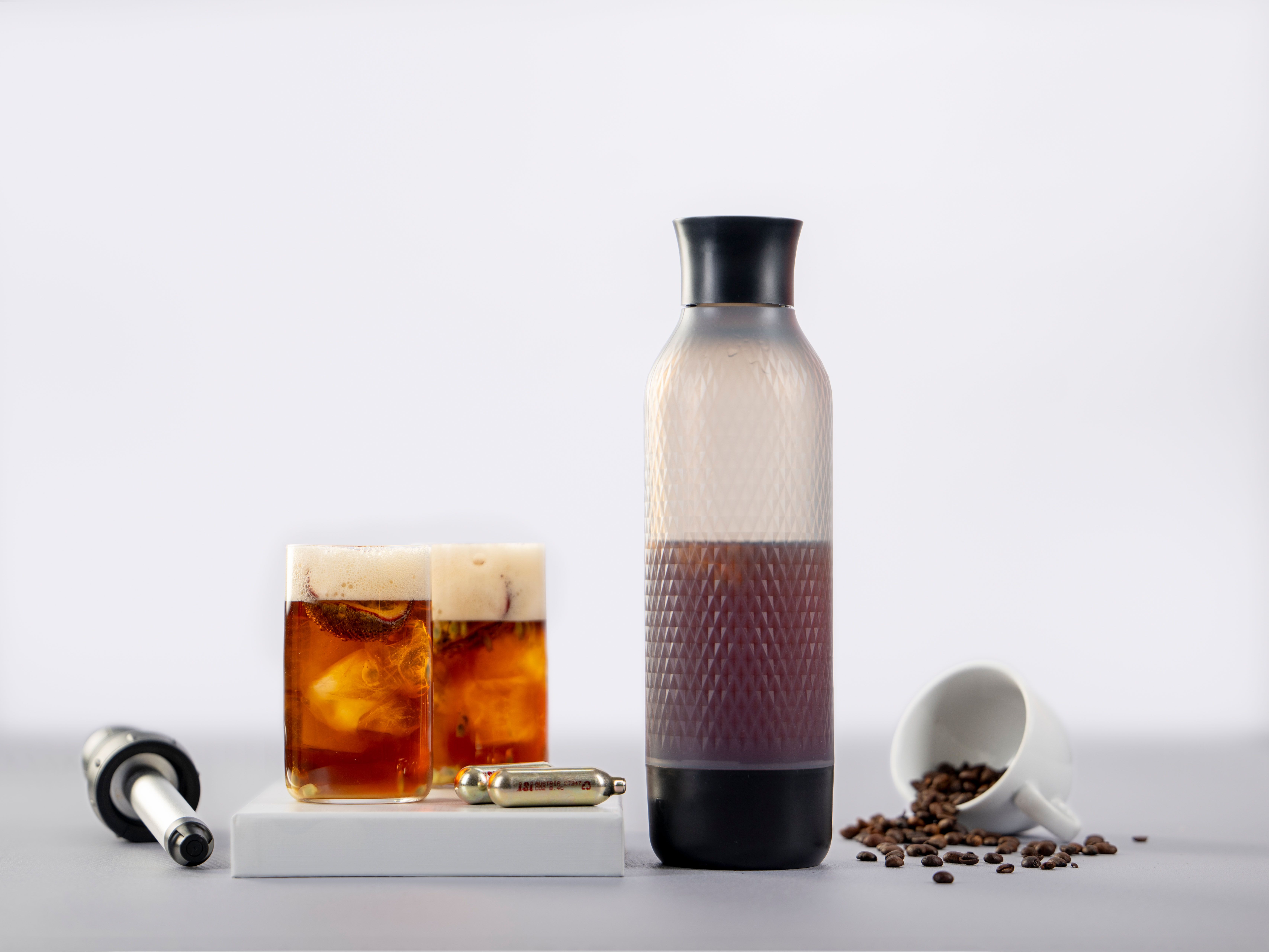 Zwei Gläser mit Sparkling Coffee, daneben iSi Charge Kapseln und ein iSi Twist'n Sparkle. 