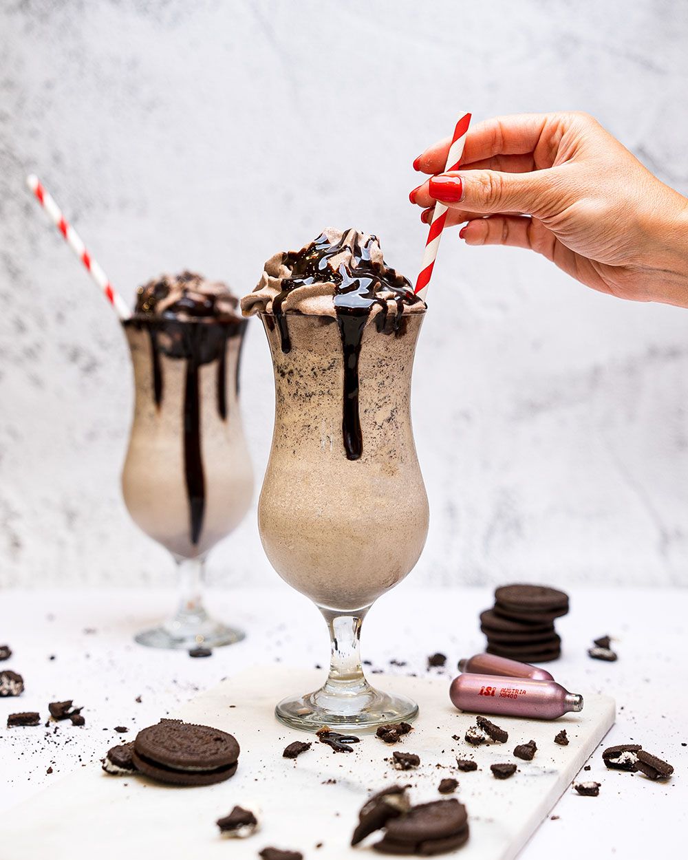 Zwei Gläser mit Oreo Kaffee Latte, daneben iSi Charge Kapseln und Oreo Kekse. 