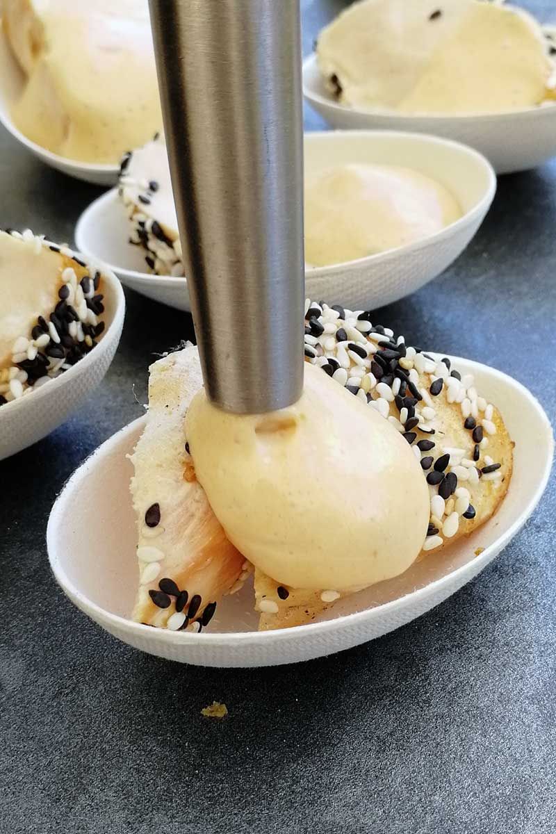 Jemand sprüht mit einem iSi Creative Whip Erdnuss Espuma in eine Schüssel. 