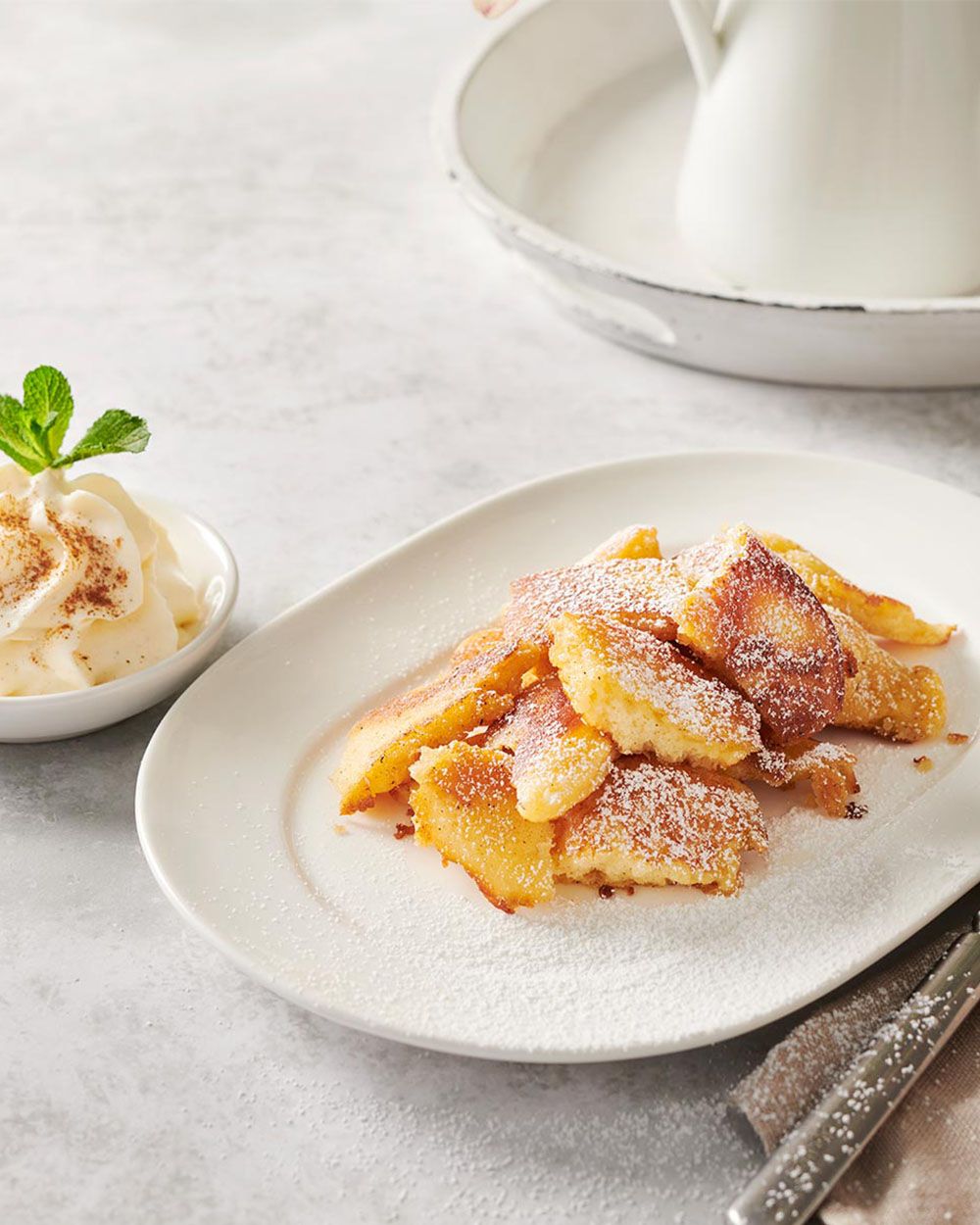 Auf einem Teller liegen Buttermilch Pancakes, daneben steht eine Schüssel mit Schaum. 