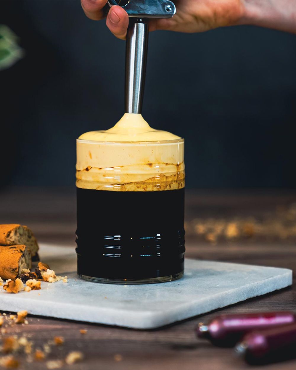 Jemand sprüht Eischaum auf ein Kaffeegetränk.