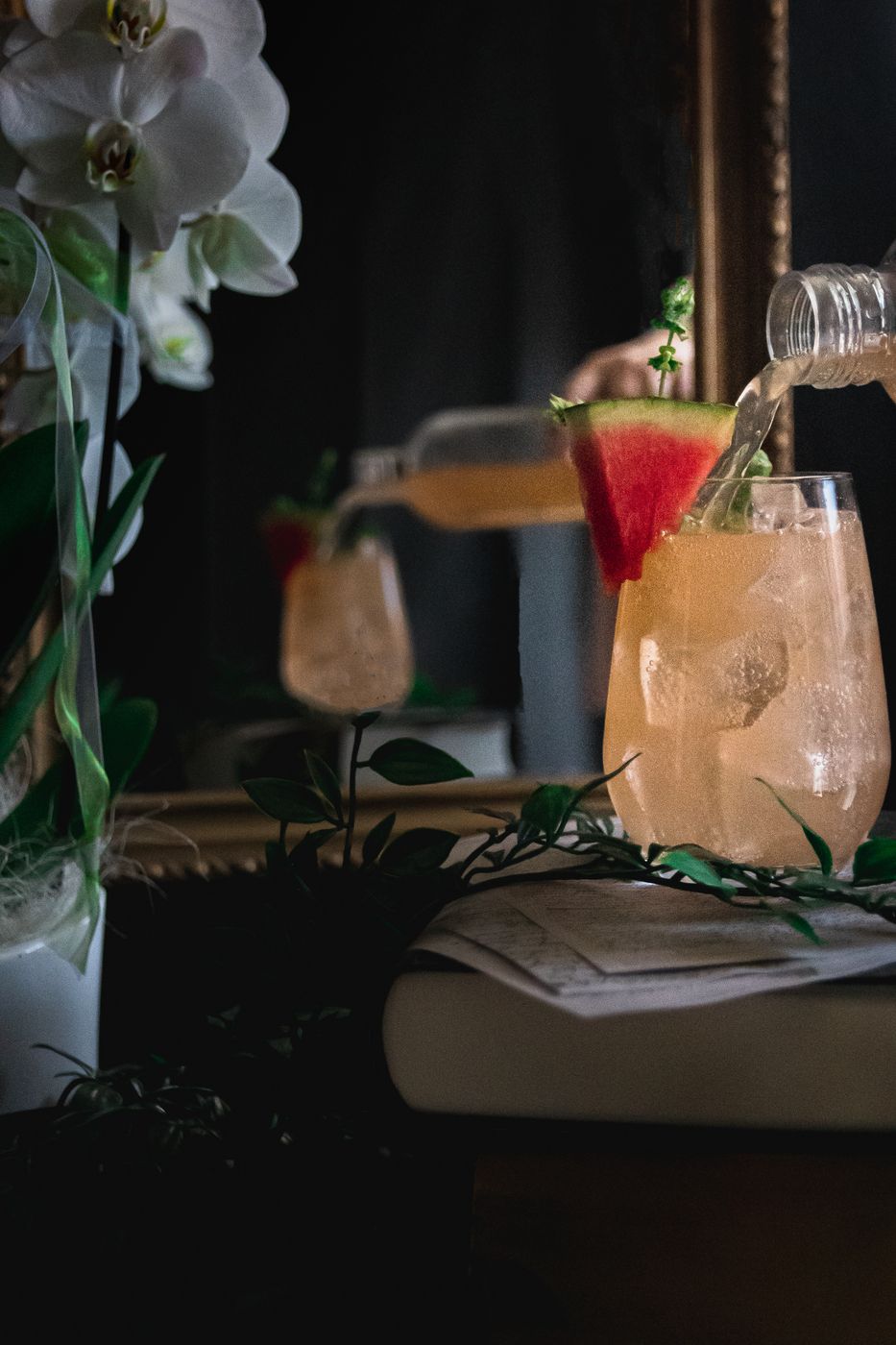 Jemand gießt Melonen-Basilikum-Spritz in ein dekoriertes Glas. 