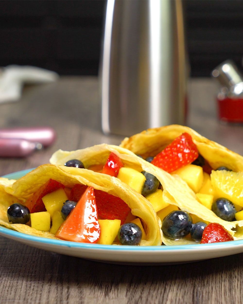Ein Teller mit Palatschinken gefüllt mit Früchten. Im Hintergrund ein iSi Gourmet Whip.