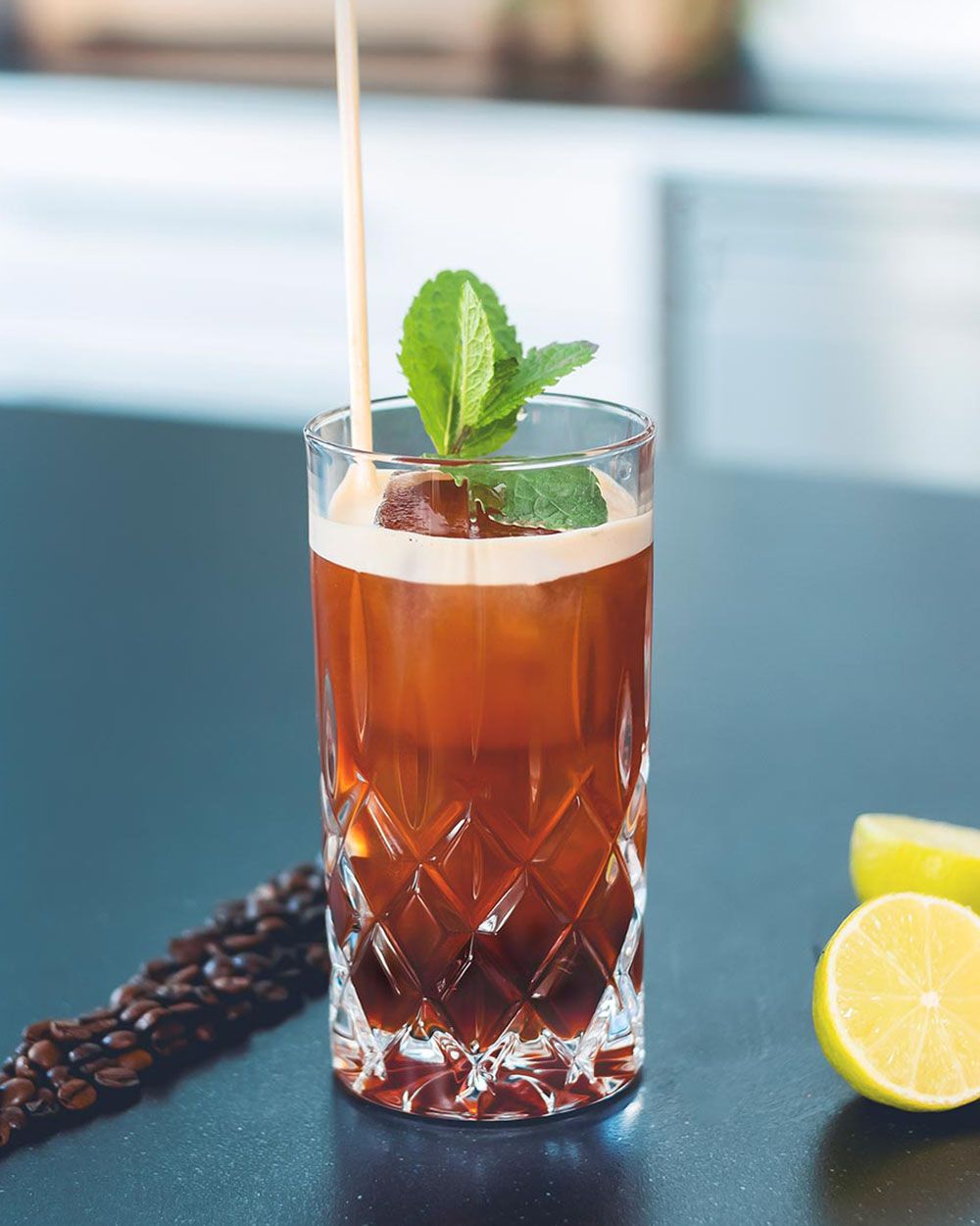 Ein Glas mit Ginger-Lemon Coldbrew, daneben Kaffeebohnen und eine Zitrone 