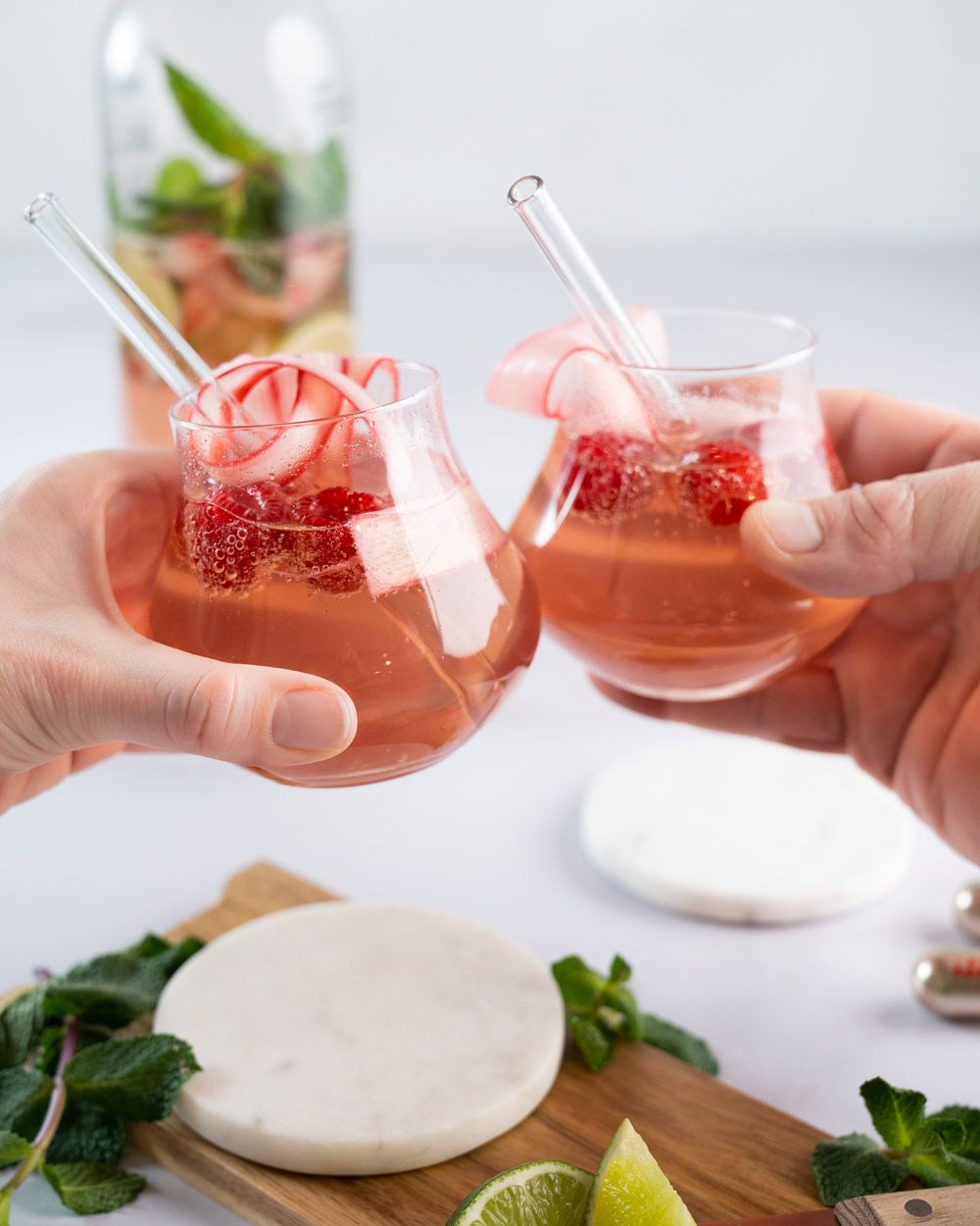 Zwei Gläser mit Virgin Rhabarber Mojito werden zum Anstoßen benutzt, im Hintergrund ein iSi Soda Maker. 