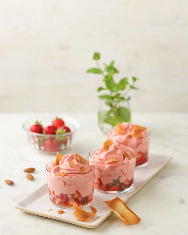 Drei Gläser mit Erdbeermousse. Im Hintergrund Erdbeeren.