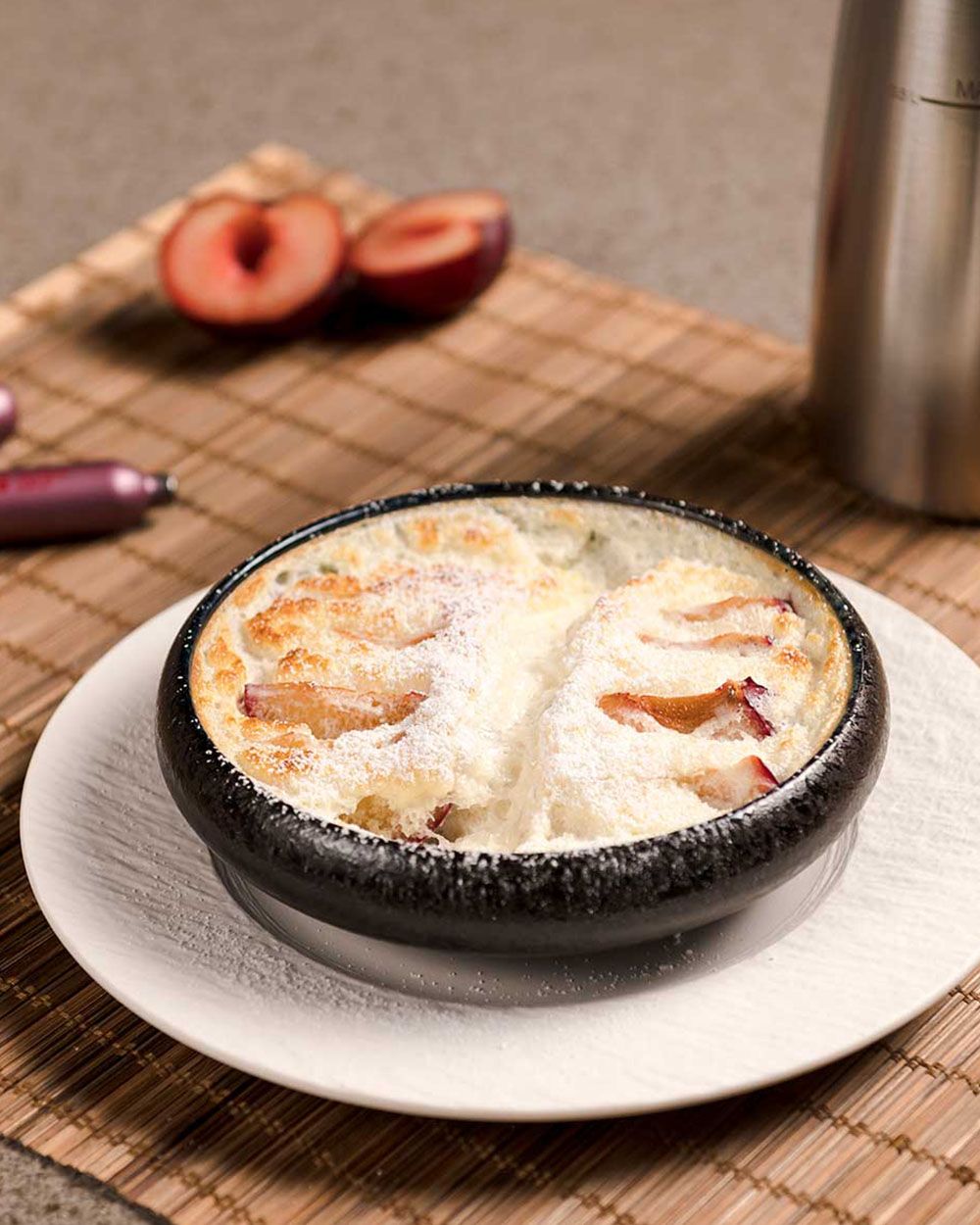 Ein Teller mit japanischem Käsekuchen, im Hintergrund eine Pflaume und iSi Charge Kapseln. 