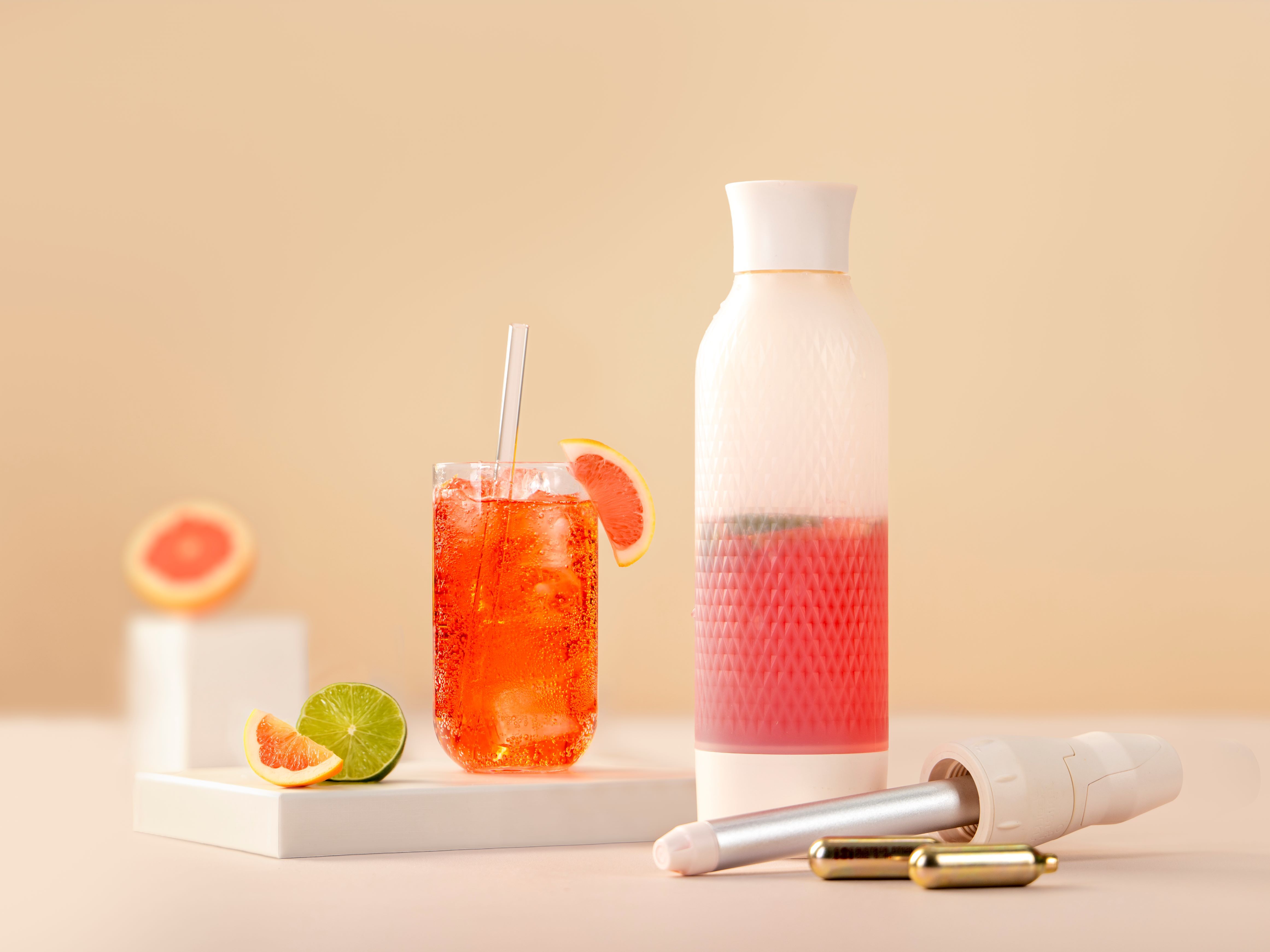 Ein Glas mit Paloma Twist, daneben ein iSi Twist'n Sparkle, iSi Charge Kapsel, Grapefruit und Limetten.