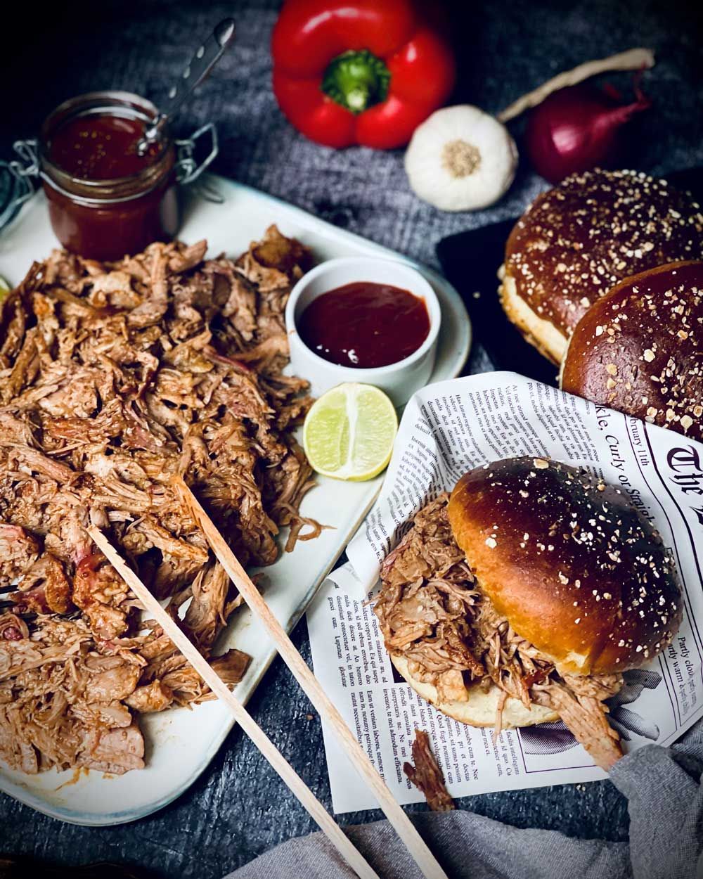 Ein Teller mit Pulled Pork, daneben Burger-Buns und Sauce. 