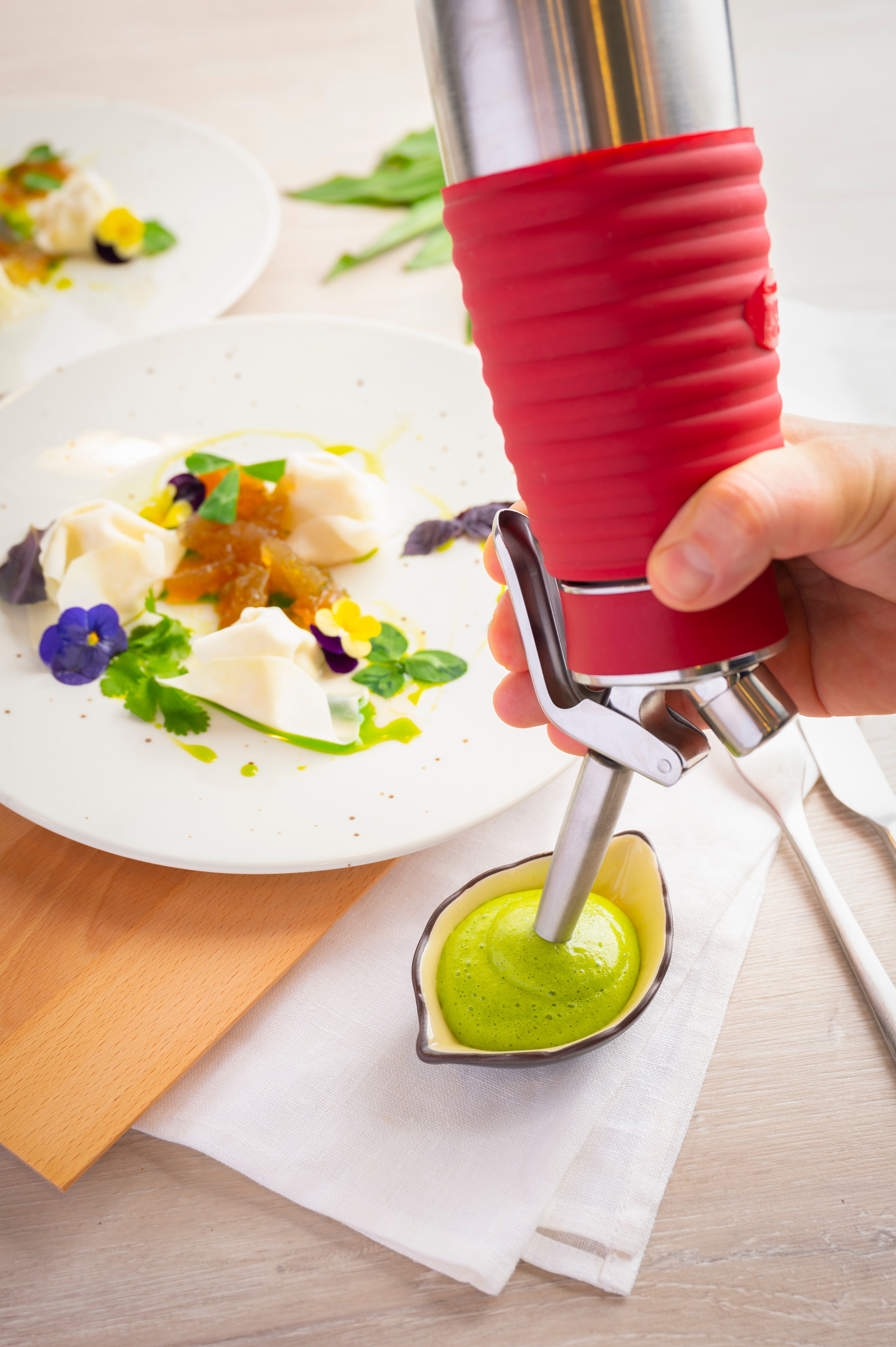 Jemand sprüht mit einem iSi Gourmet Whip Bärlauchsauce in eine Schüssel. 