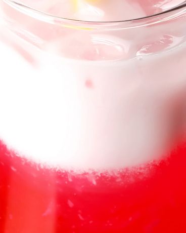 Ein Glas mit einem rot-weißen Schichtgetränk ist mit Eiswürfeln gefüllt und von oben fotografiert.
