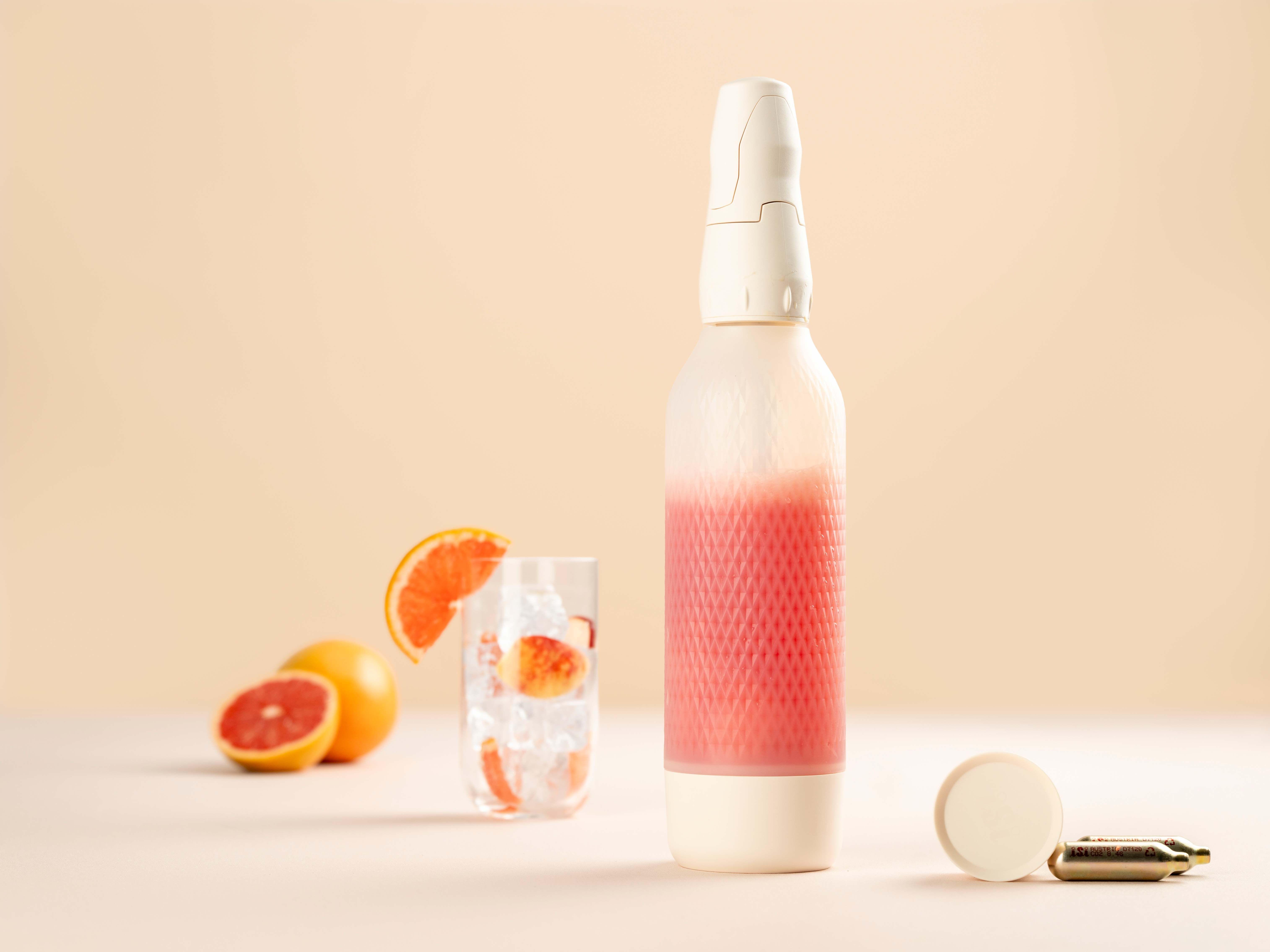 Ein Glas mit Eis, daneben ein iSi Twist'n Sparkle mit Sparkling Pomegranate Paloma Tea. 