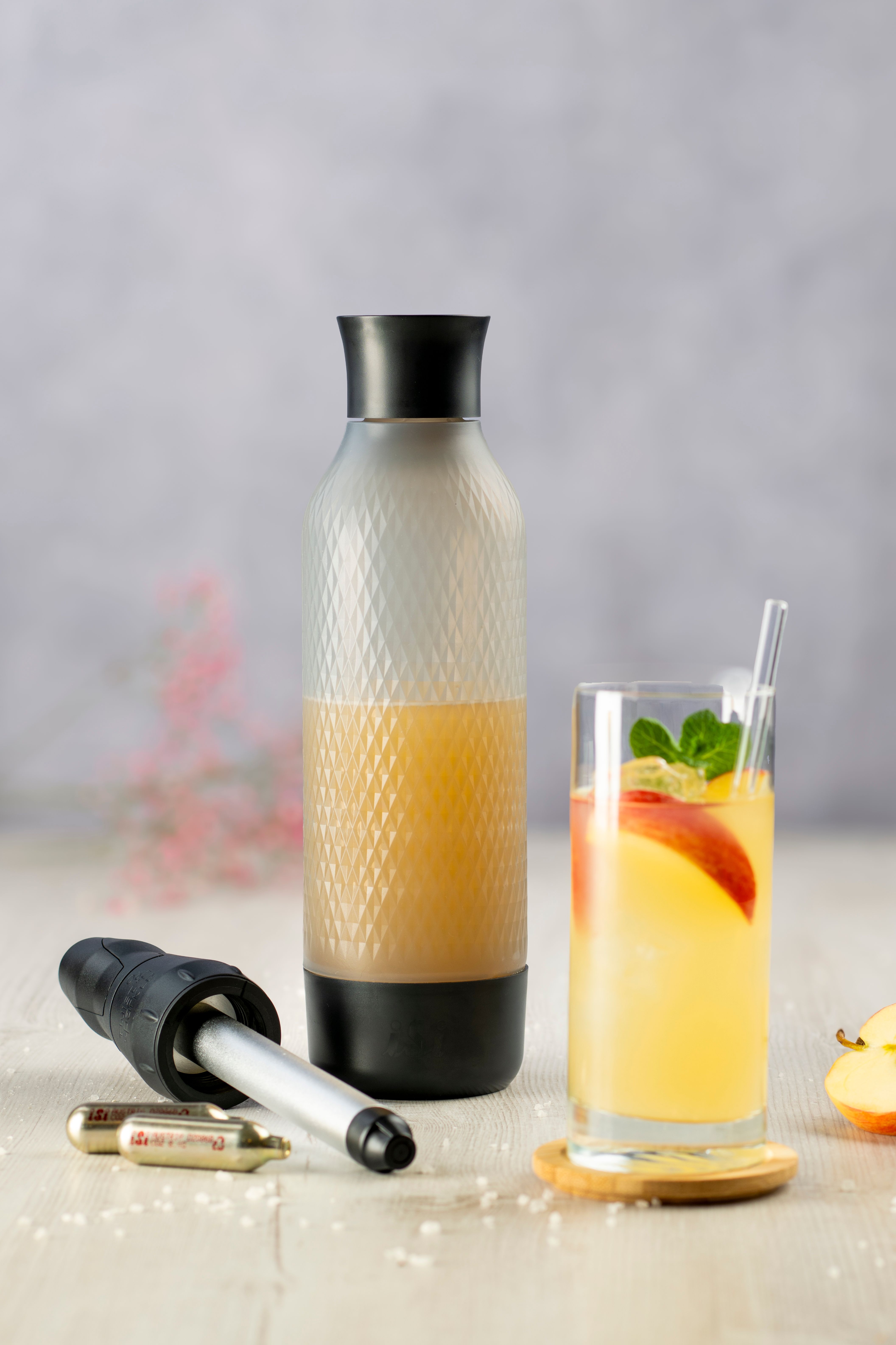 Ein iSi Twist'n Sparkle, daneben iSi Charge Kapseln und ein Glas mit Electro Fizz. 