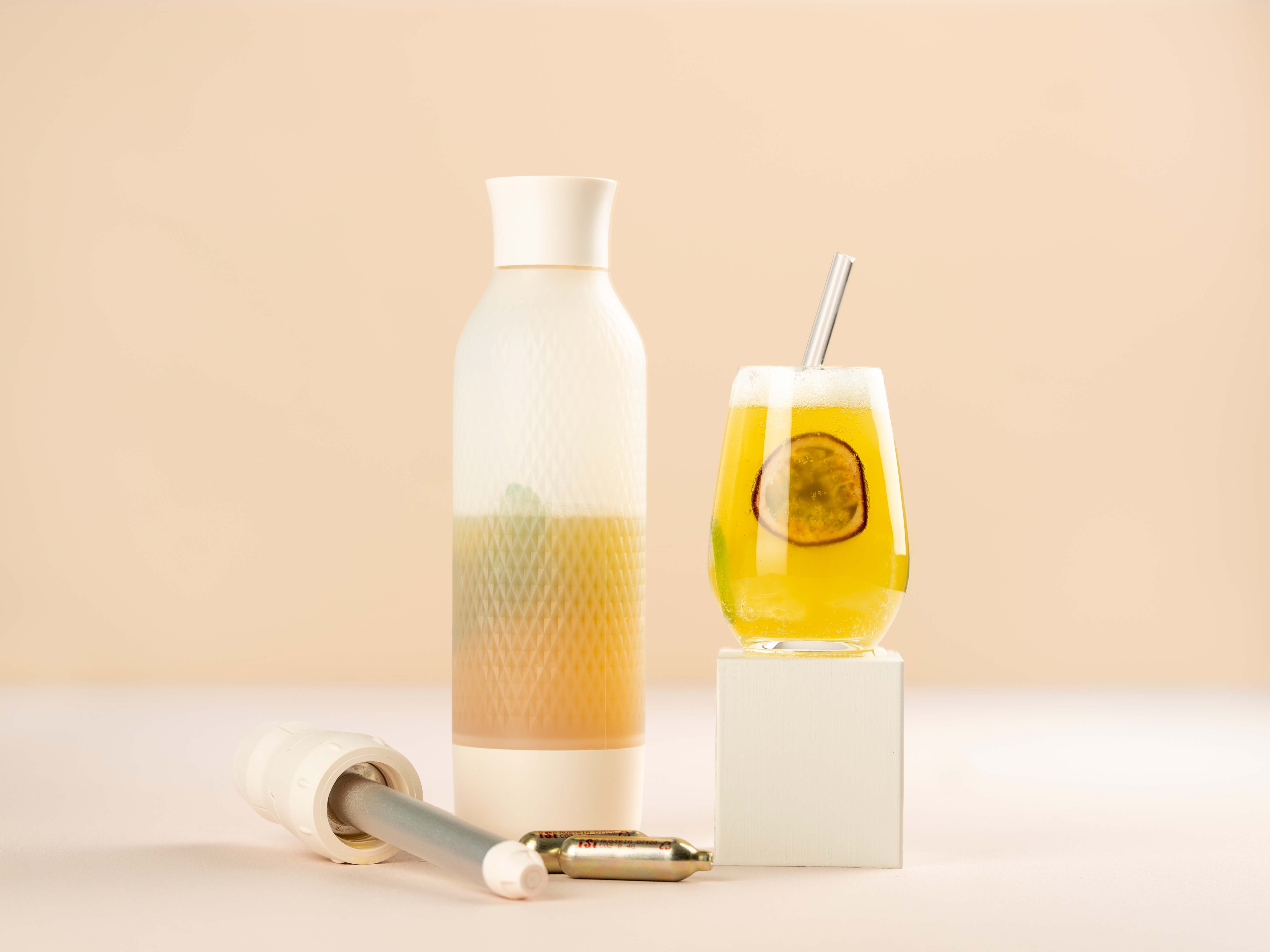 Ein Glas mit grünem Tee und Passionsfrucht, daneben iSi Charge Kapseln und ein iSi Twist'n Sparkle.