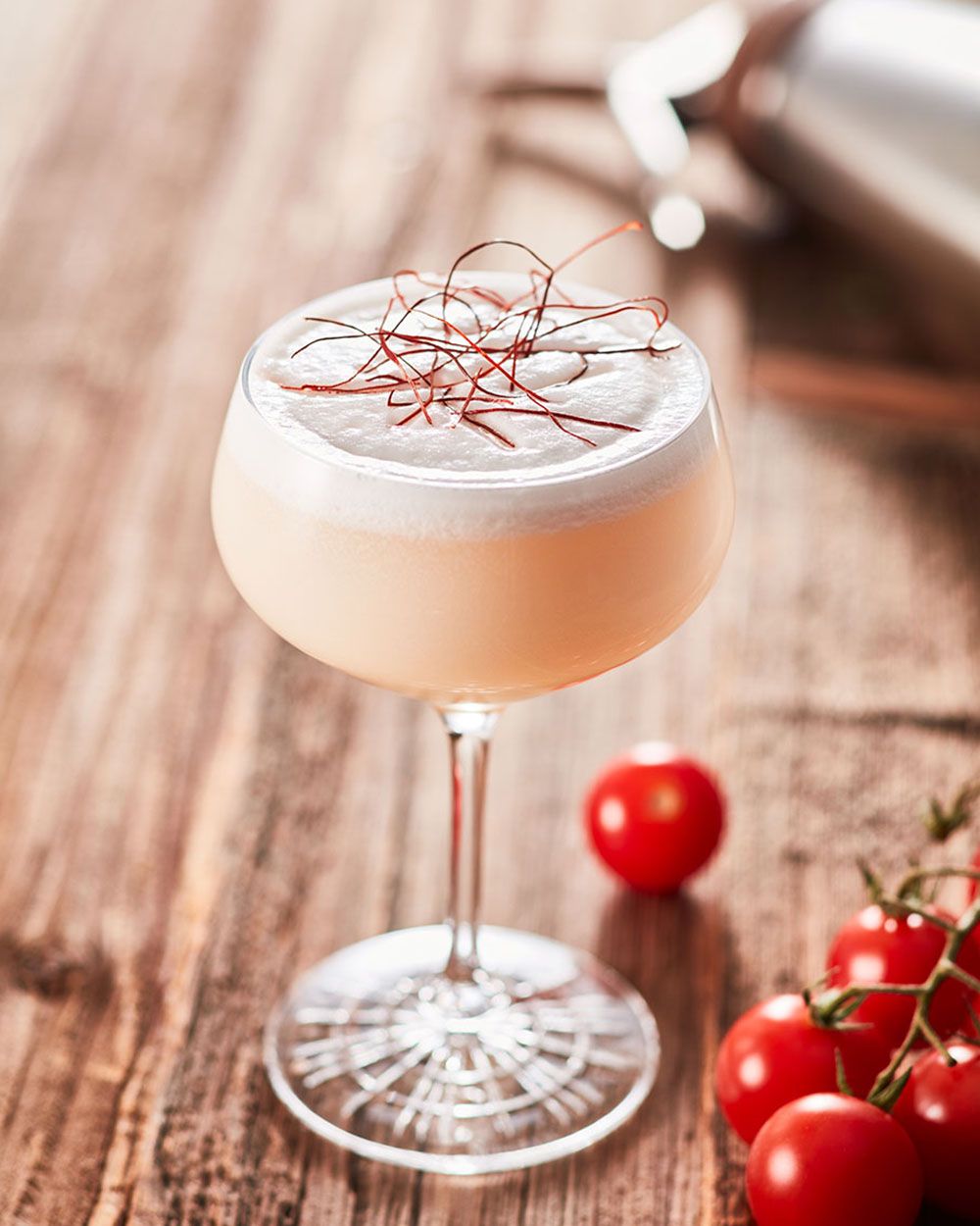 Ein Glas mit Nitro Bloody Mary, daneben Tomaten. 