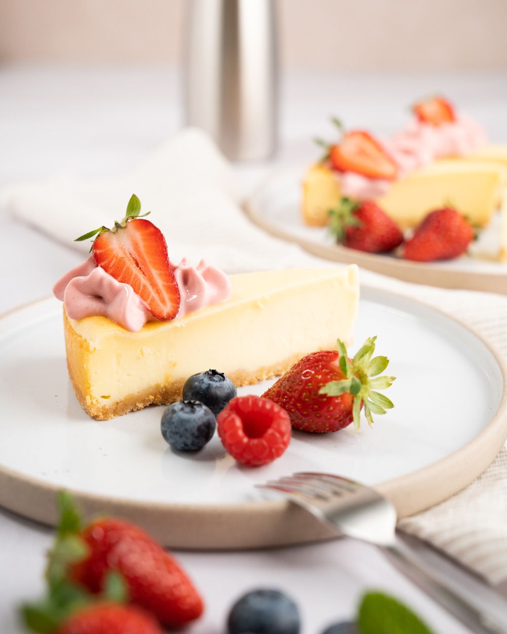 Ein Teller mit Cheesecake mit Erdbeertopping und frischen Beeren.