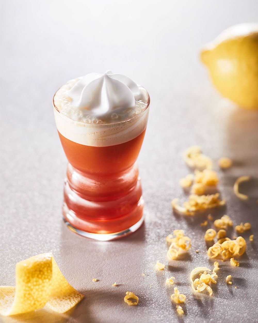 Ein kleines Glas mit Nitro Limoncello, daneben Zitronenschale. 