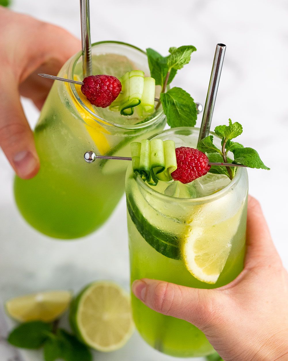 Personen stoßen mit zwei Gläsern mit Nitro Gurken Gin an. 