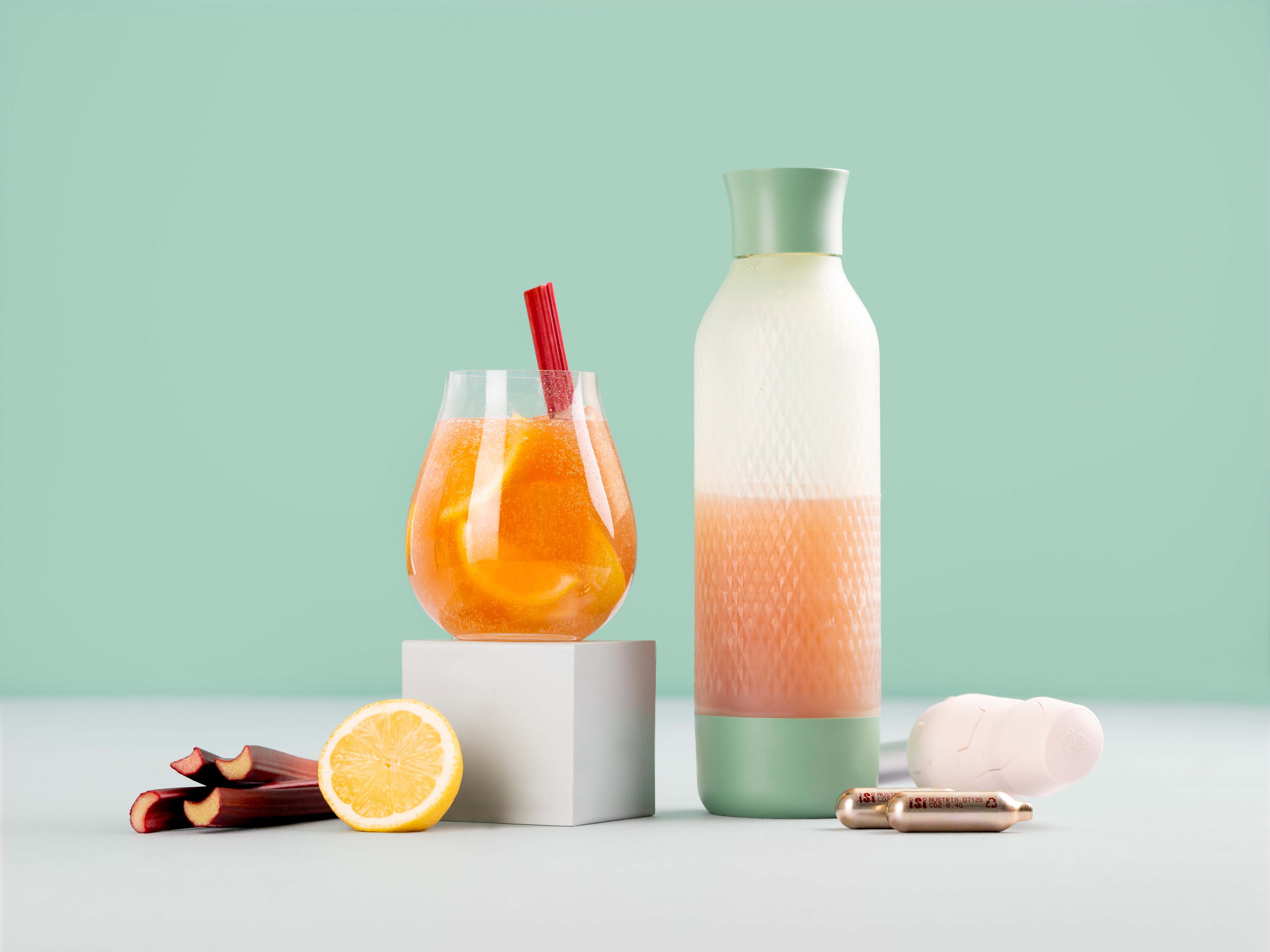 Ein Glas mit Fizzy Rhubarb, daneben ein iSi Twist'n Sparkle und iSi Charge Kapseln.