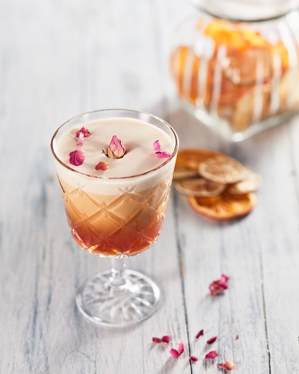 Ein Glas mit Nitro Bull, daneben getrocknete Orangen. 