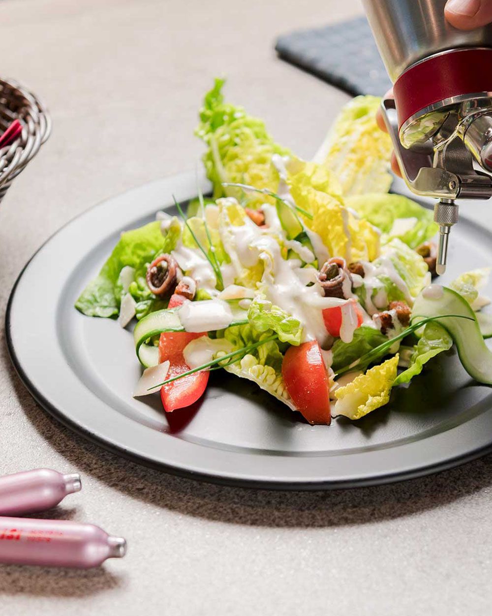 Ein Salat mit Caesar Dressing, davor liegen zwei iSi Charge Kapseln. 