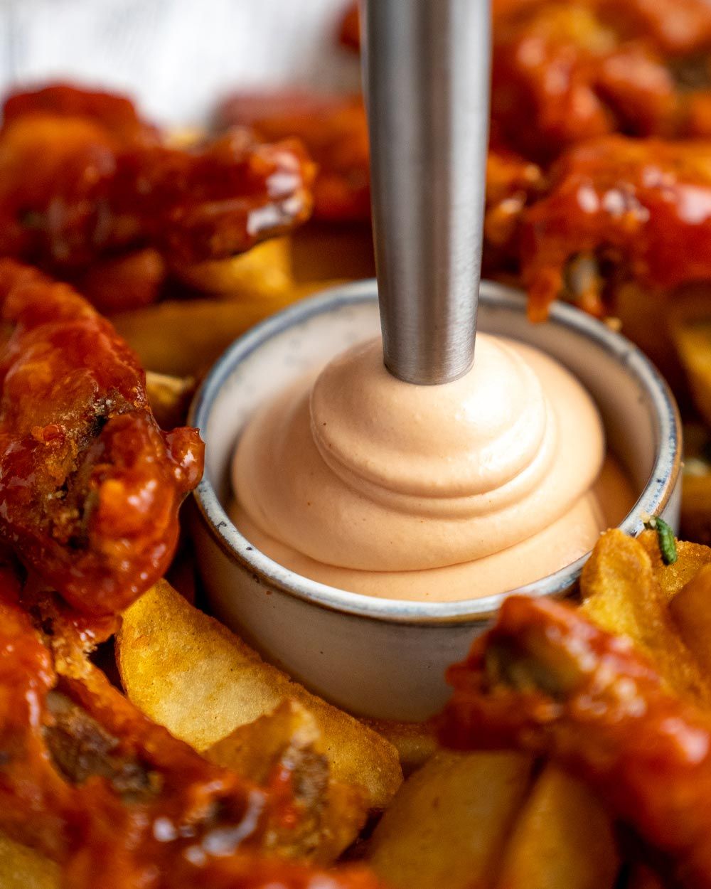 Auf dem Bild sieht man Chicken Wings mit Kartoffelspalten, Zitronenspalten und einem Dip in der Mitte.