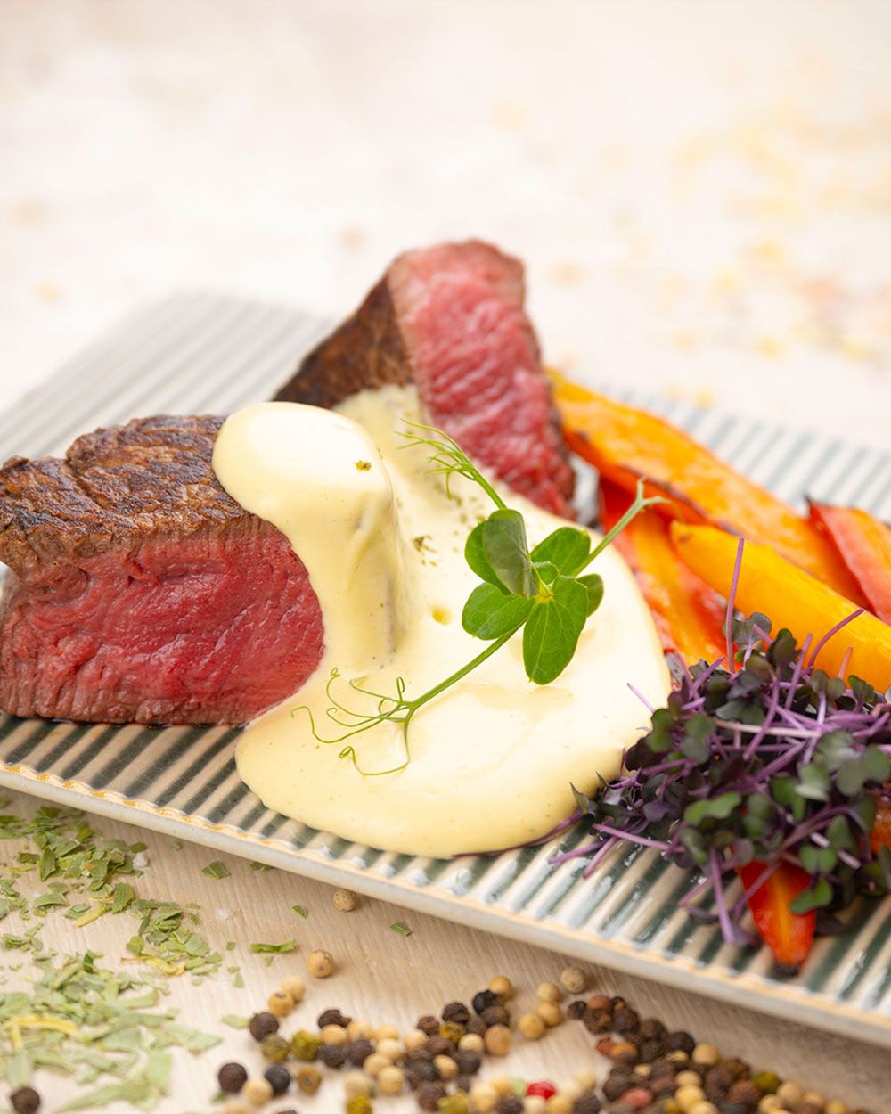 Ein Teller mit Steak, Süßkartoffel-Pommes und Sauce Bernaise. 
