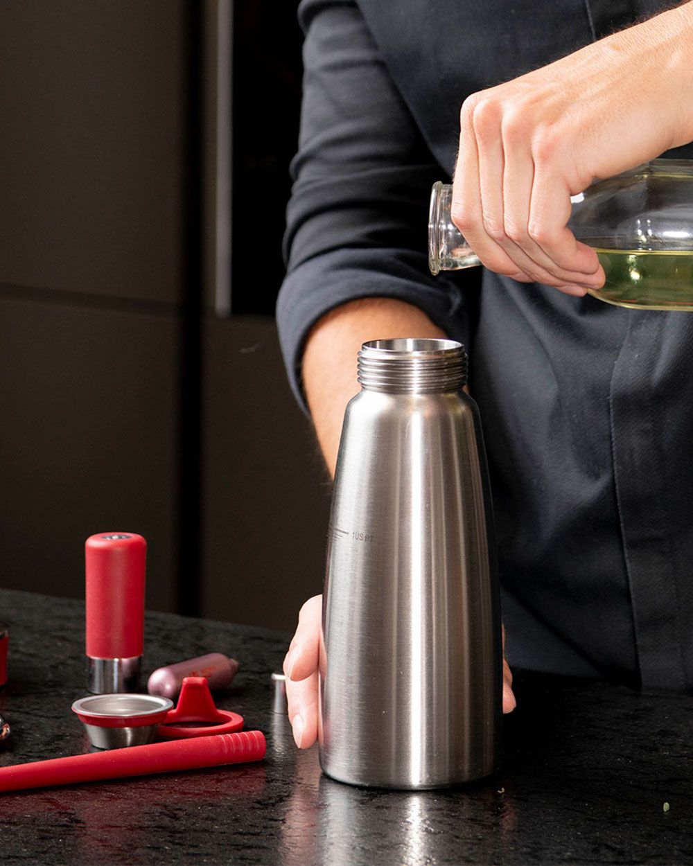 Jemand gießt Öl in eine iSi Gourmet Whip. 