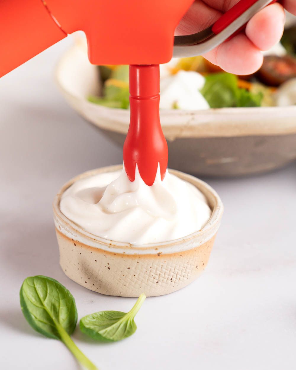 Jemand sprüht mit einen iSi Creative Whip Sour Cream Dressing in eine Schüssel.