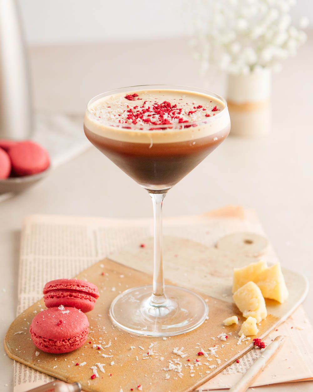 Ein Glas mit Nitro Espresso Martini, daneben Macarons. 