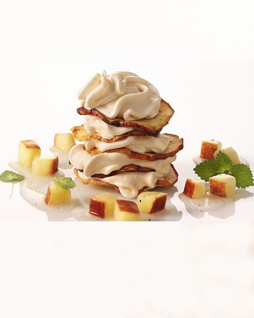 Auf dem Bild ist ein Dessert aus geschichteten Apfelchips mit Creme sowie kleinen Apfelwürfeln und frischer Minze angerichtet.