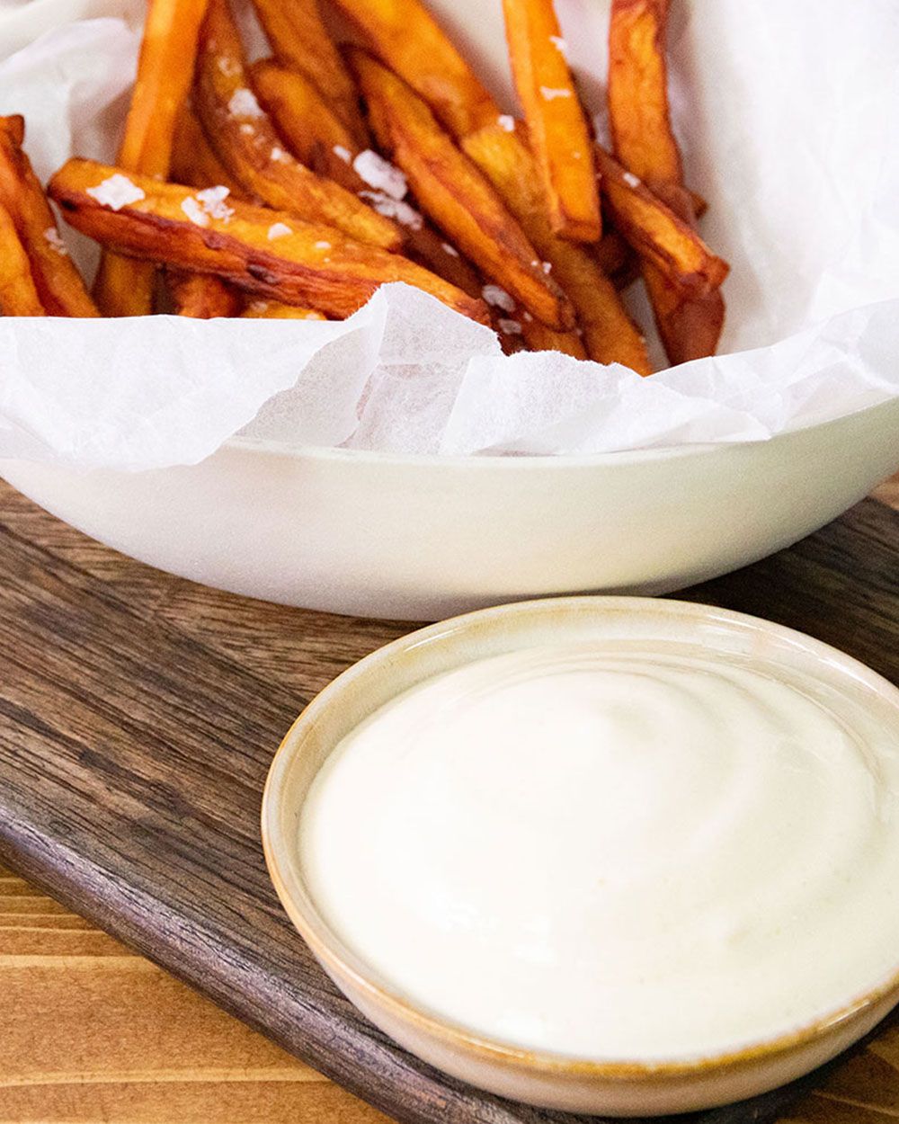 Eine Schüssel mit Aioli Sacue, daneben ein Teller mit Süßkartoffel-Pommes.