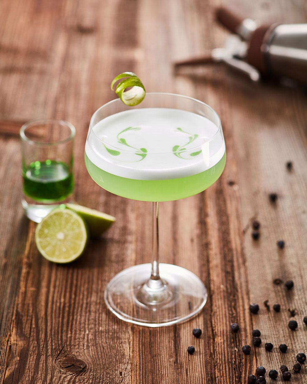 Ein Glas mit Nitro Tonic Sour, daneben ein Shot Absinth und Limetten. 