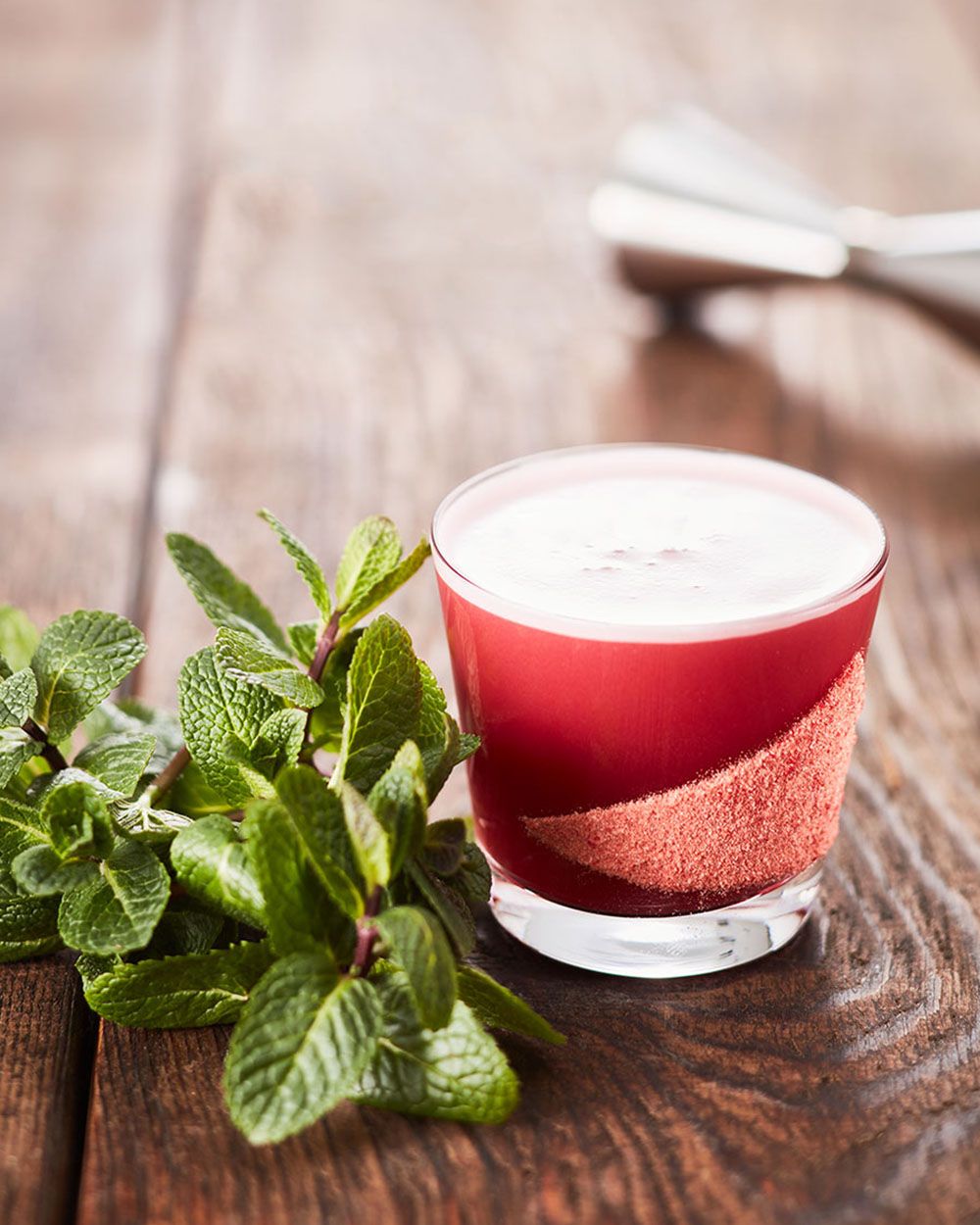 Ein Glas mit Nitro Kombucha Red, daneben Minze. 