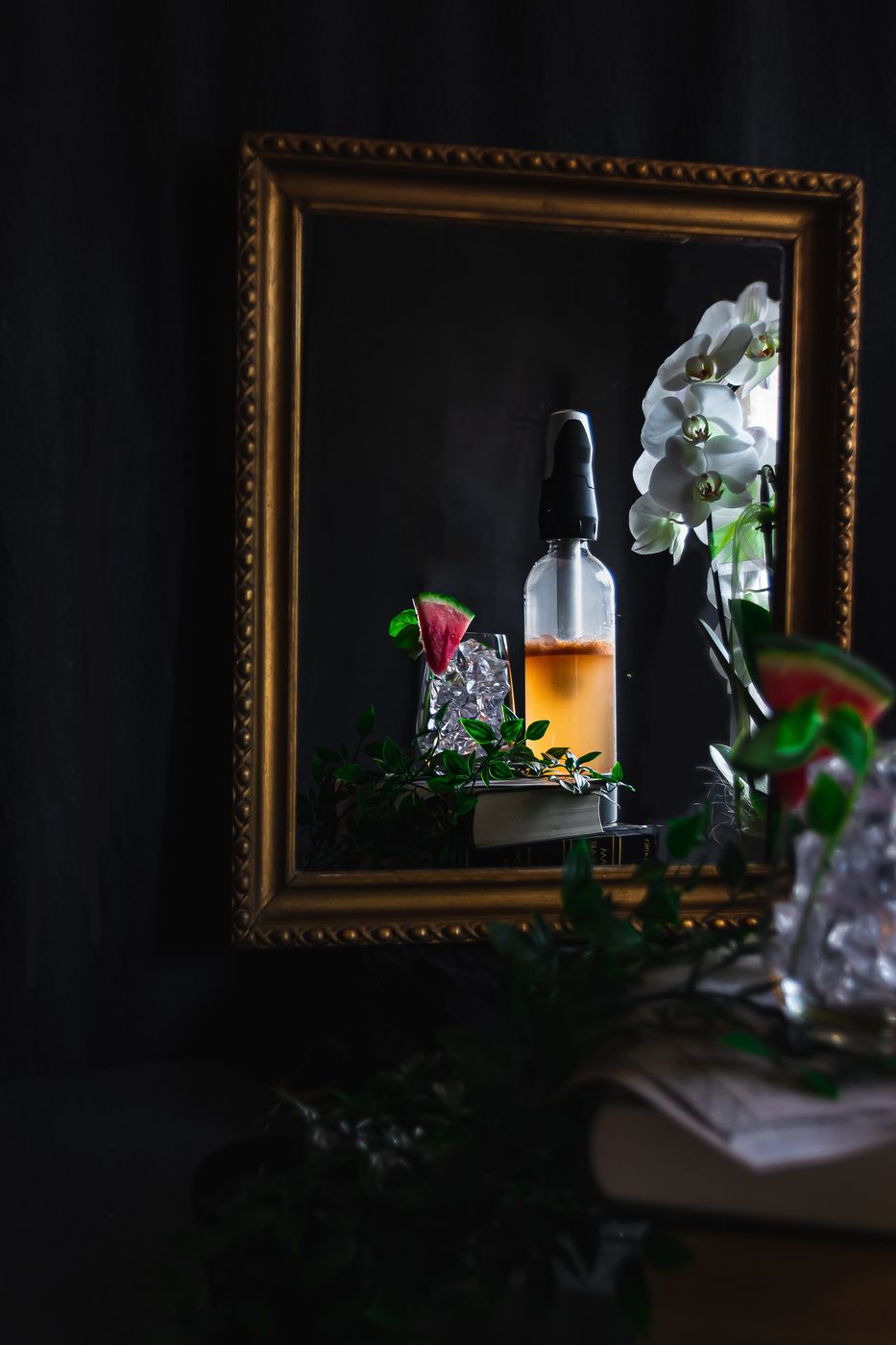 In einem Spiegel mit goldenem Rand ist ein Basil-Melon-Spritz zu sehen, daneben ein iSi-Sodamaker und eine Orchidee.