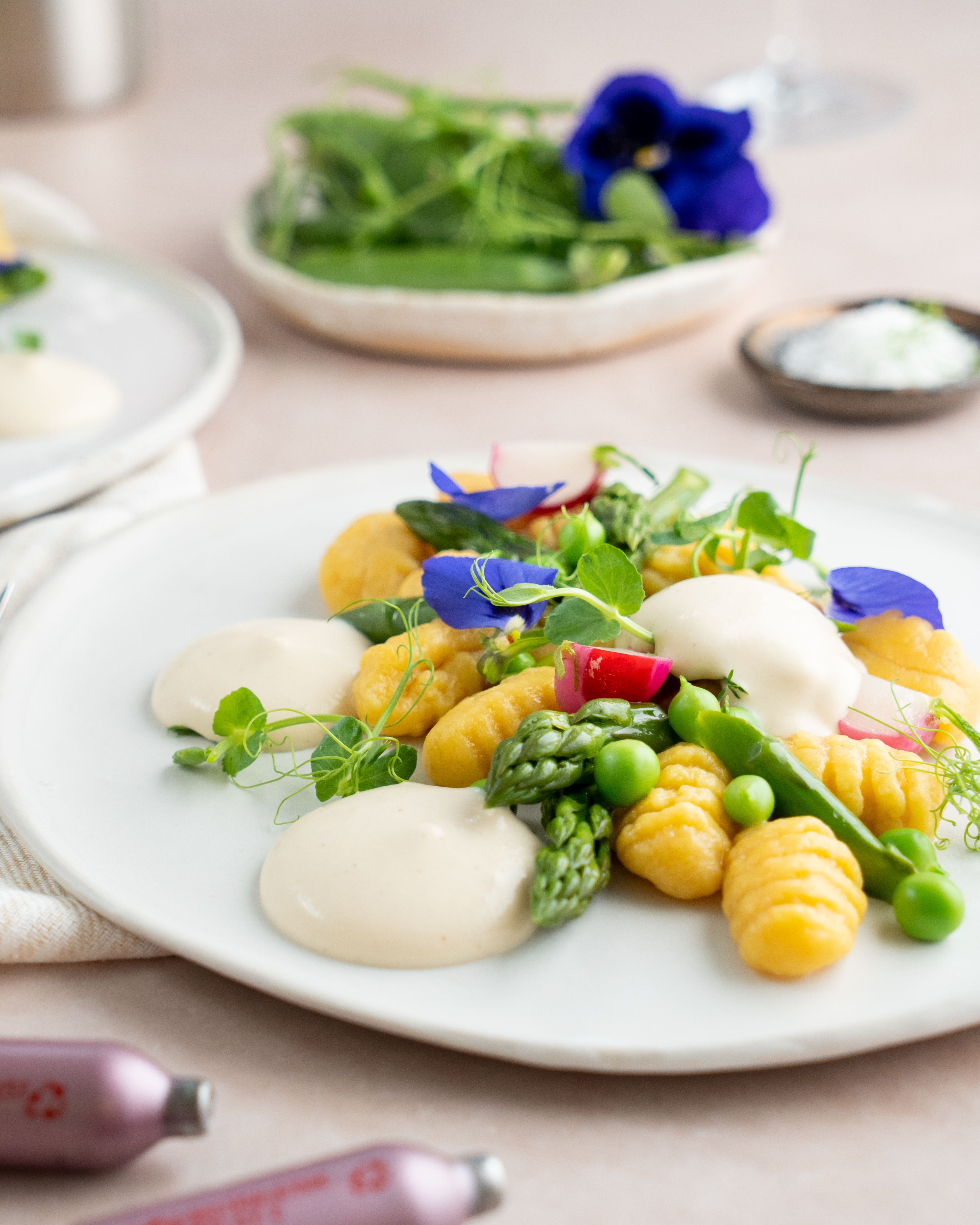 Ein Teller mit Gnocchi, Gemüse und Spargel-Espuma, daneben iSi Charge Kapseln. 