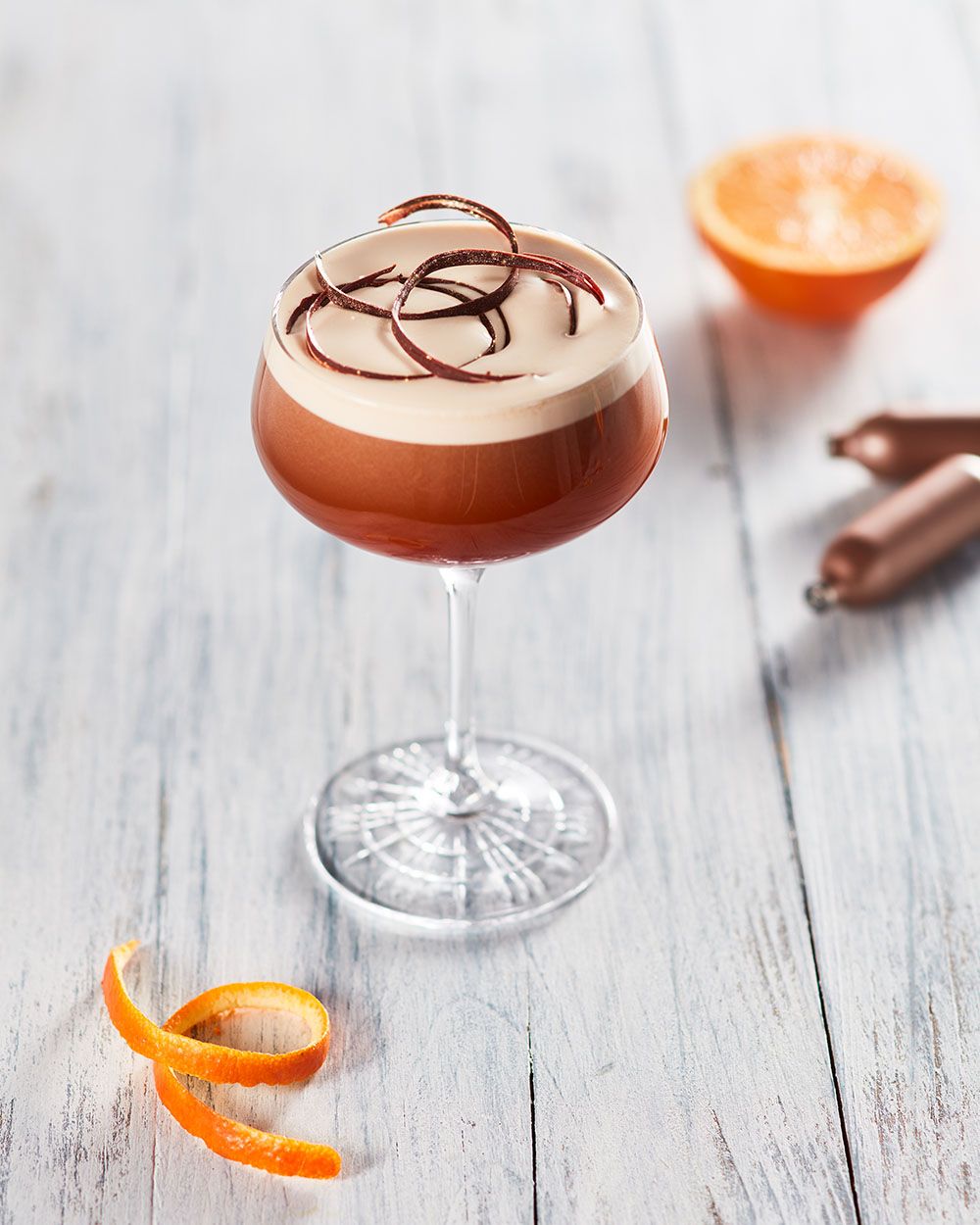 Ein Glas mit Nitro Grand Manier, daneben Orangenschale und iSi Charge Kapseln. 