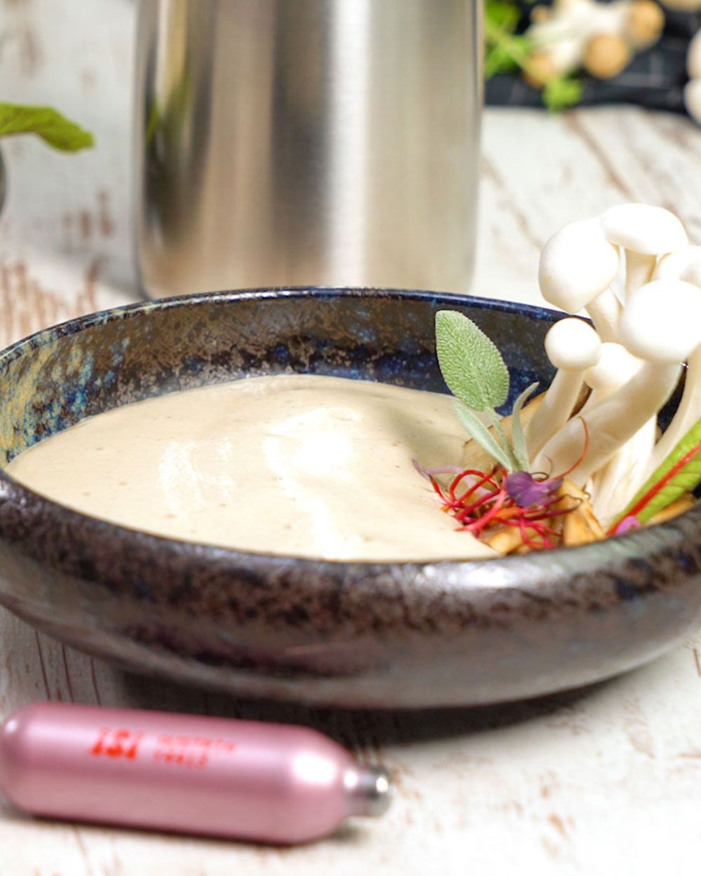 EIn Teller mit Pilzsuppe, davor eine iSi Charge Kapsel.