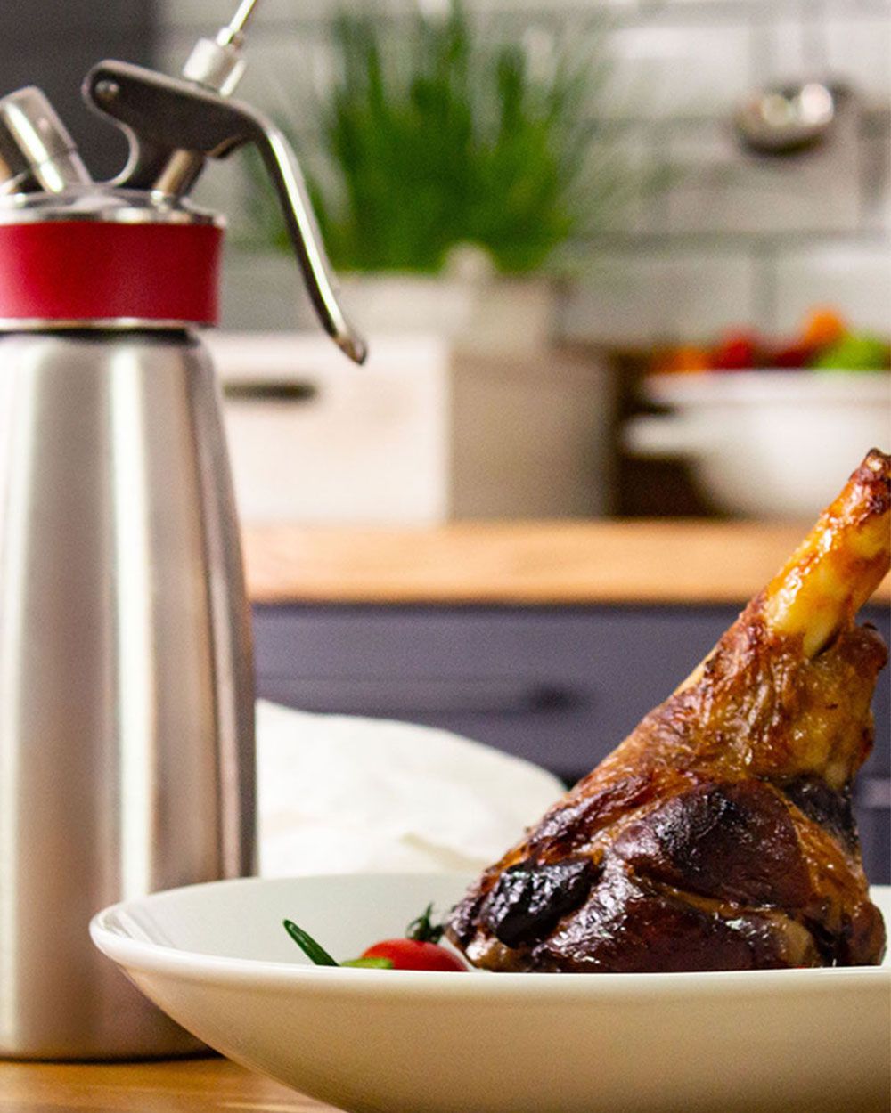 Ein Teller mit einem Stück Lamm, daneben ein iSi Gourmet Whip. 