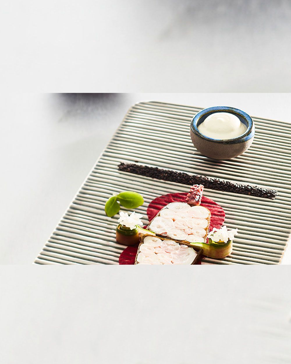 Ein Teller mit Pulpo, daneben eine Schüssel mit Wasabi Espuma. 