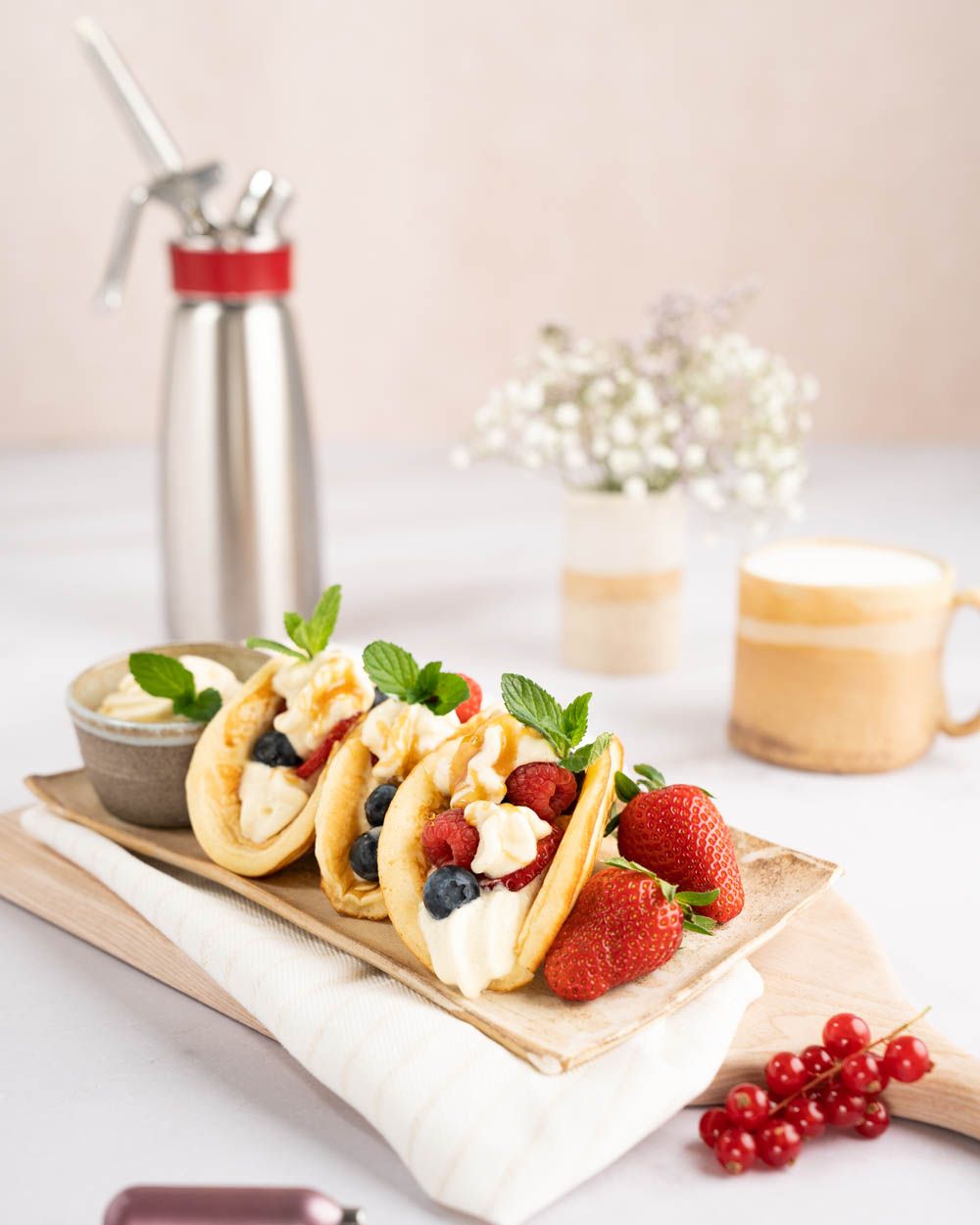 Dessert-Tacos mit Beeren und Vanille-Mascarpone-Creme, im Hintergrund Kaffee und ein iSi Gourmet Whip.