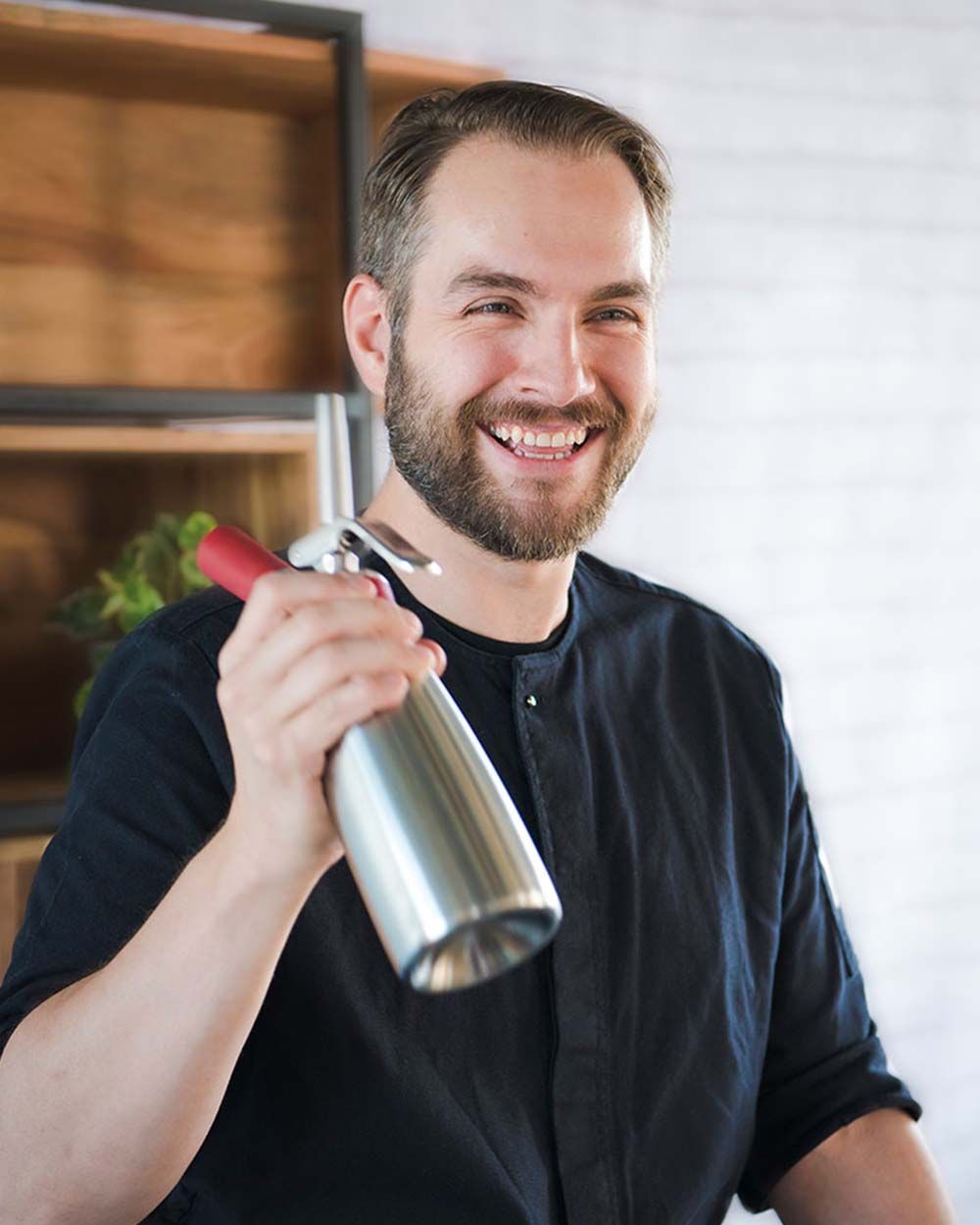 Ein lachender Mann hält ein iSi Gourmet Whip.